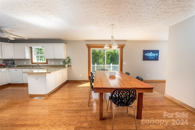 dining room with a textured ceiling, ceiling fan, light hardwood / wood-style floors, and a healthy amount of sunlight