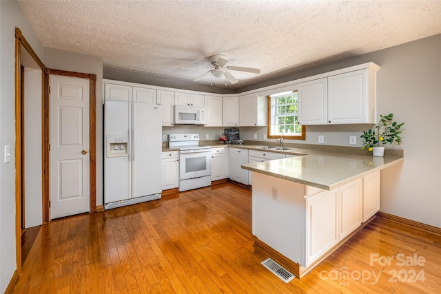 kitchen featuring white appliances, kitchen peninsula, white cabinets, and sink