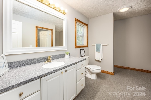 bathroom featuring toilet, vanity, and a textured ceiling