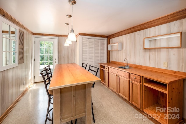 kitchen featuring decorative light fixtures, a kitchen island, wood counters, and sink