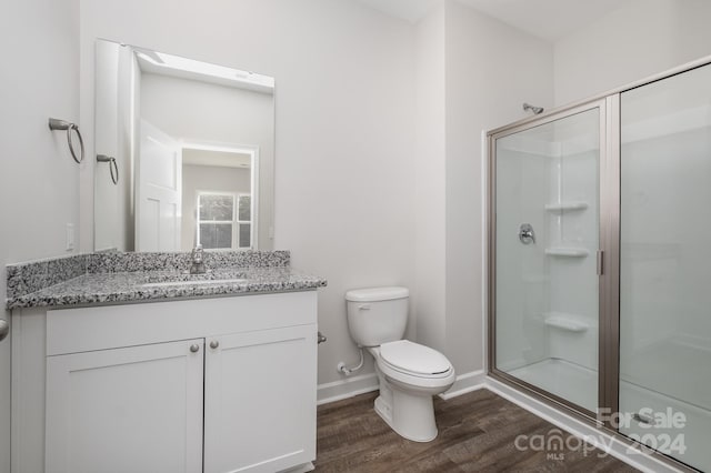 bathroom featuring hardwood / wood-style floors, toilet, a shower with shower door, and vanity