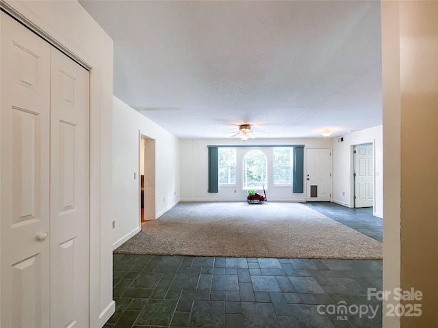 spare room with ceiling fan, a textured ceiling, and dark carpet