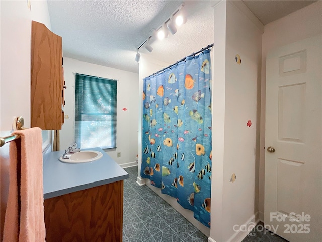 bathroom featuring a textured ceiling, walk in shower, vanity, and rail lighting