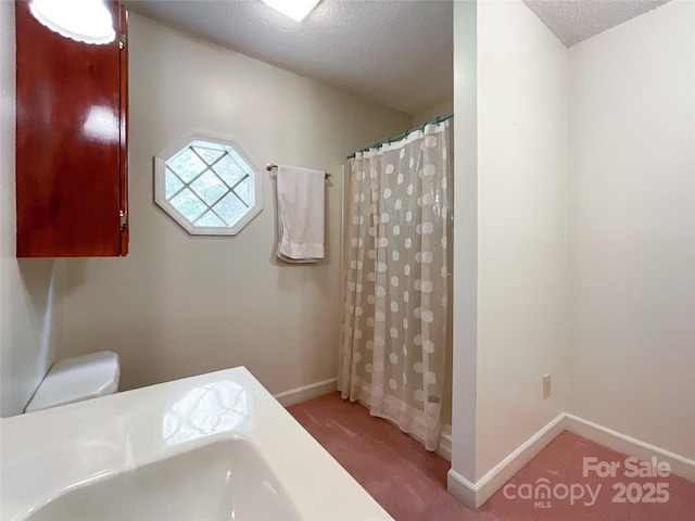 bathroom featuring a textured ceiling, curtained shower, and toilet