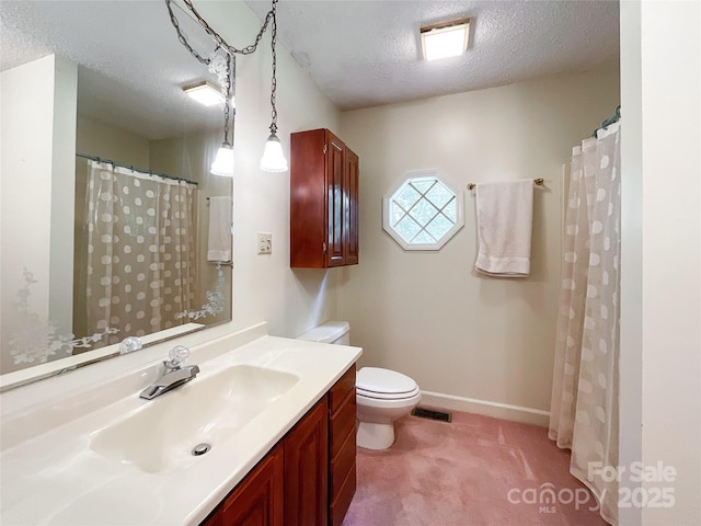 bathroom featuring a textured ceiling, vanity, and toilet