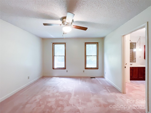 carpeted spare room with ceiling fan and a textured ceiling