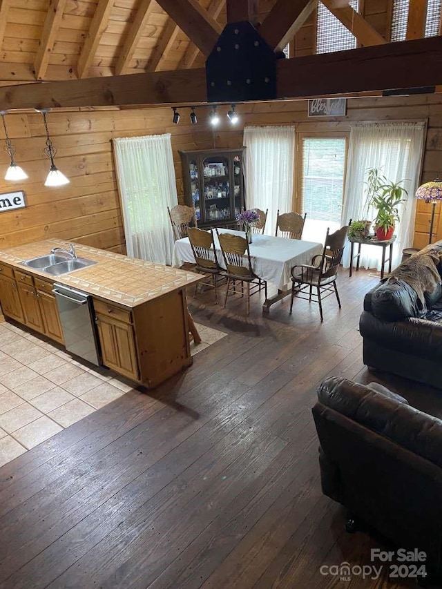 interior space featuring hanging light fixtures, beamed ceiling, sink, dishwasher, and light hardwood / wood-style floors