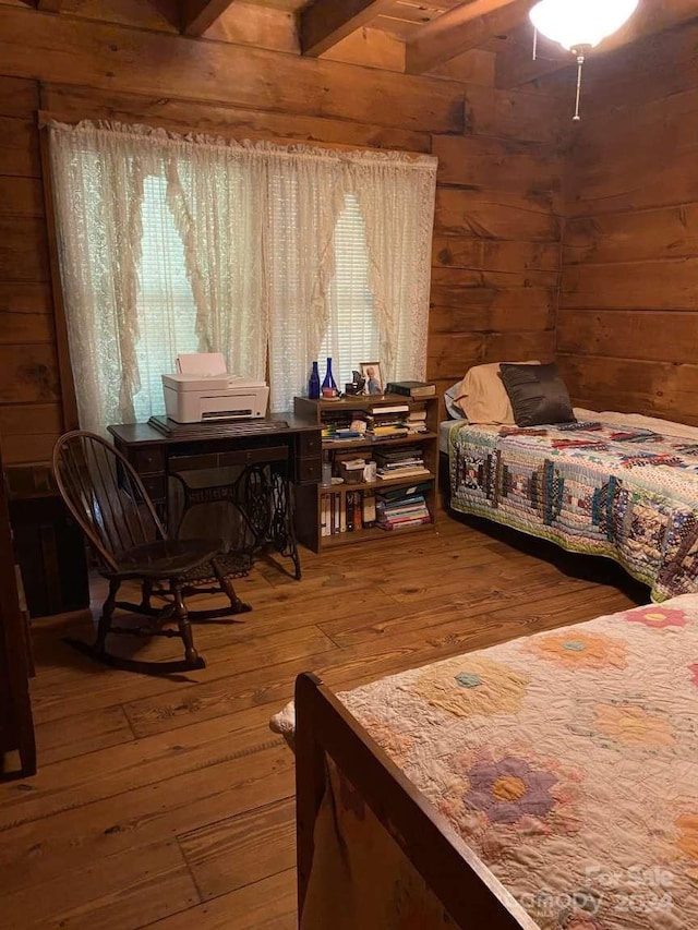 bedroom with beamed ceiling, wooden walls, and hardwood / wood-style floors