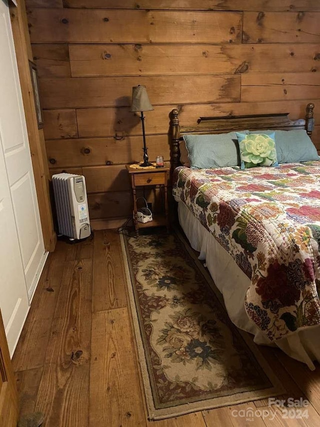 bedroom with wood-type flooring and wooden walls