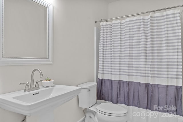 bathroom featuring toilet, a shower with curtain, and sink