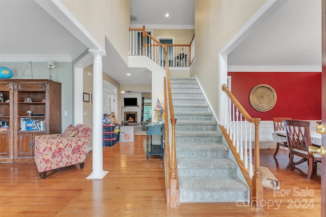 stairway with hardwood / wood-style flooring, ornate columns, and ornamental molding