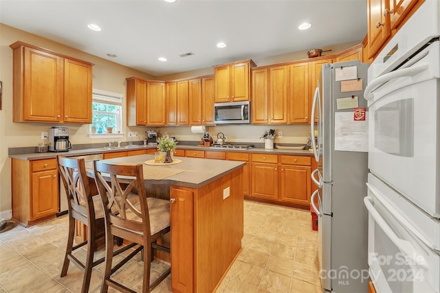 kitchen with a kitchen breakfast bar, stainless steel appliances, a kitchen island, and sink