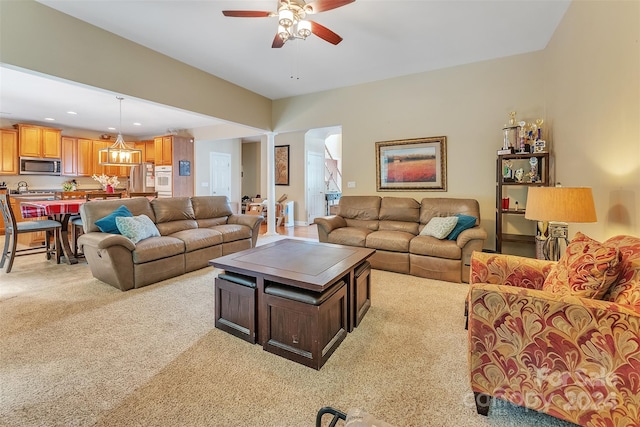 carpeted living room with decorative columns and ceiling fan