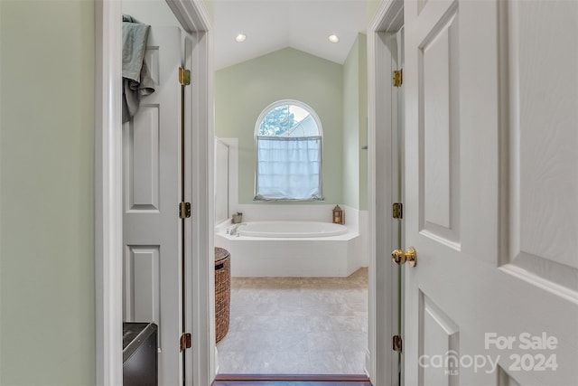 bathroom featuring a relaxing tiled tub and lofted ceiling