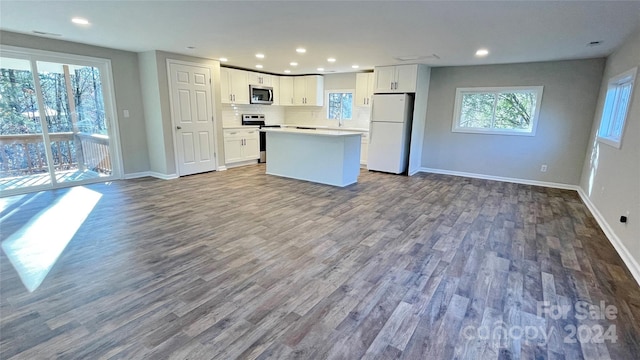 kitchen featuring white cabinetry, hardwood / wood-style floors, a center island, decorative backsplash, and stainless steel appliances