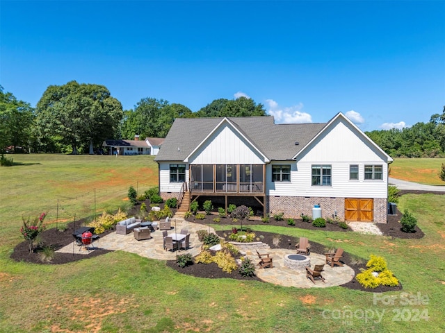 rear view of house featuring a sunroom, a patio, a yard, and an outdoor living space with a fire pit