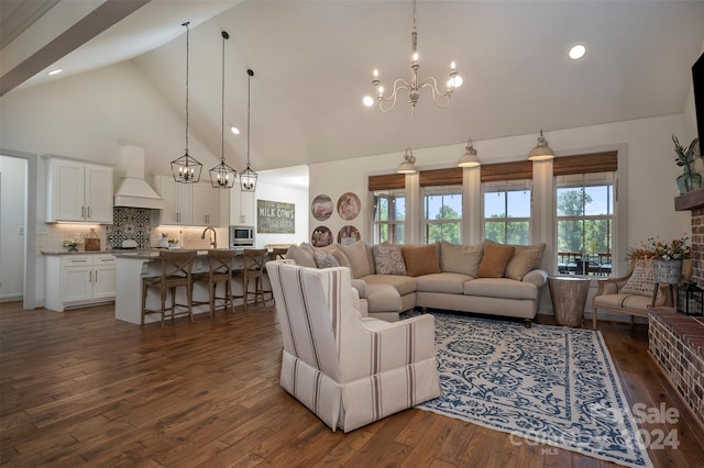 living room featuring an inviting chandelier, dark hardwood / wood-style flooring, sink, and high vaulted ceiling