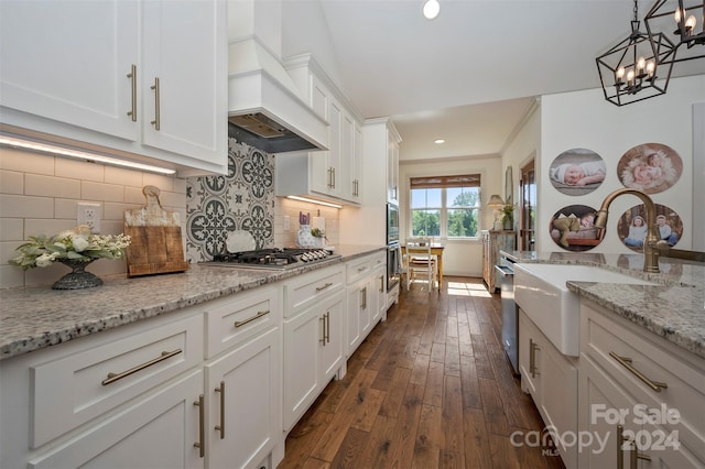 kitchen featuring pendant lighting, appliances with stainless steel finishes, white cabinetry, dark hardwood / wood-style floors, and custom range hood