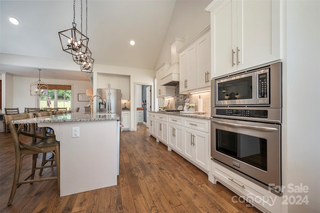 kitchen featuring white cabinetry, stainless steel appliances, and a center island with sink