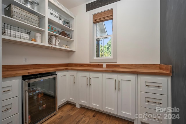 bar with wooden counters, beverage cooler, white cabinetry, and light hardwood / wood-style floors