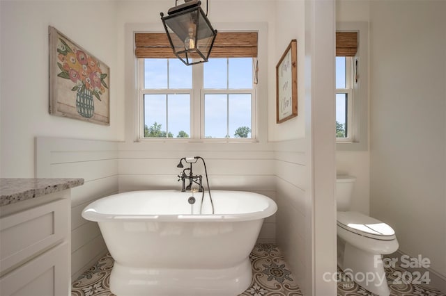 bathroom featuring toilet, a bath, vanity, and tile patterned flooring