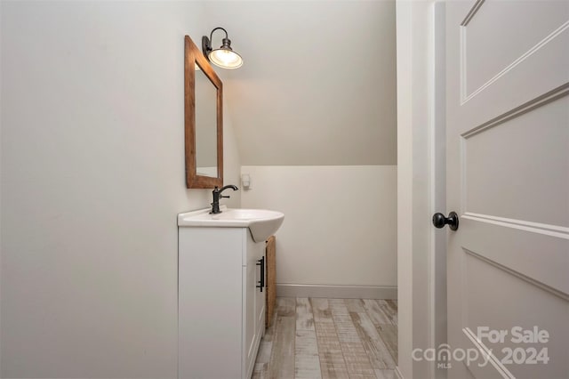 bathroom with vaulted ceiling, hardwood / wood-style flooring, and vanity