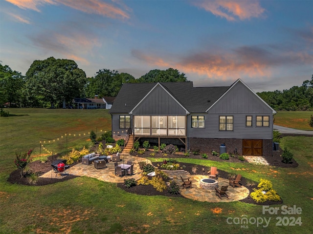 back house at dusk featuring a yard, a patio, and a sunroom