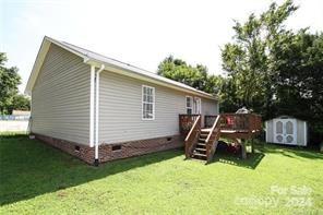 back of house featuring a deck, a yard, and a storage shed