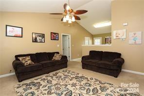 living room with ceiling fan, vaulted ceiling, and carpet