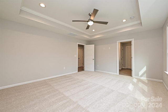 unfurnished bedroom with a tray ceiling, ceiling fan, crown molding, and light colored carpet