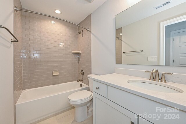 full bathroom featuring tile patterned floors, vanity, tiled shower / bath combo, and toilet