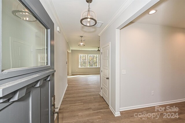 hallway with dark hardwood / wood-style flooring, an inviting chandelier, and ornamental molding