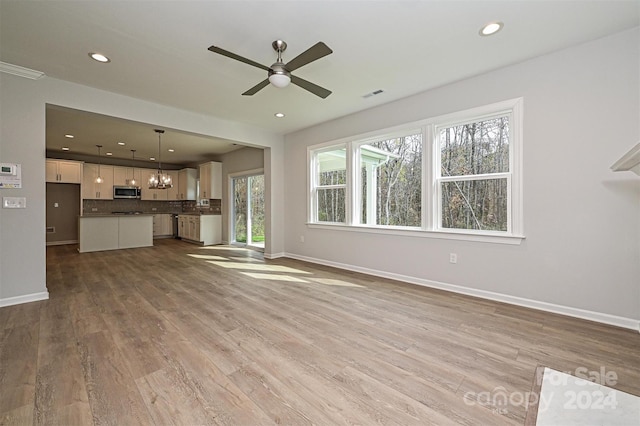 unfurnished living room with ceiling fan with notable chandelier and light wood-type flooring