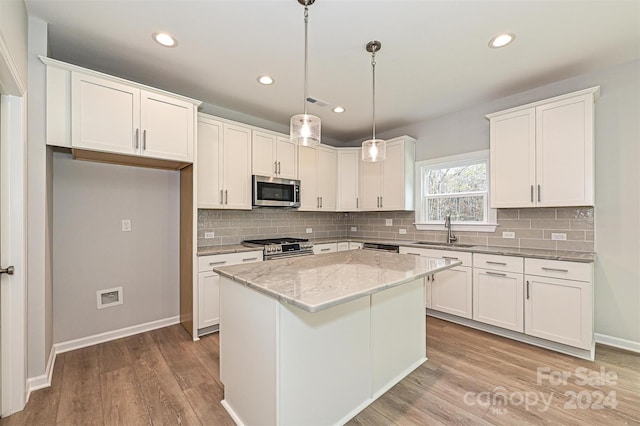 kitchen featuring a center island, white cabinetry, stainless steel appliances, and hanging light fixtures