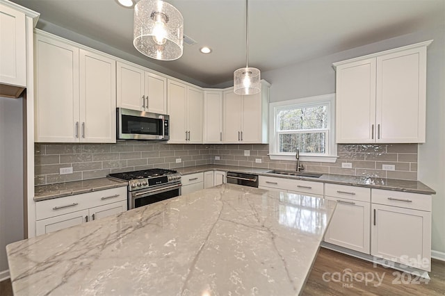 kitchen with appliances with stainless steel finishes, decorative light fixtures, white cabinetry, and sink