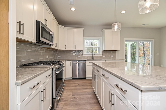 kitchen with a healthy amount of sunlight, sink, stainless steel appliances, and decorative light fixtures