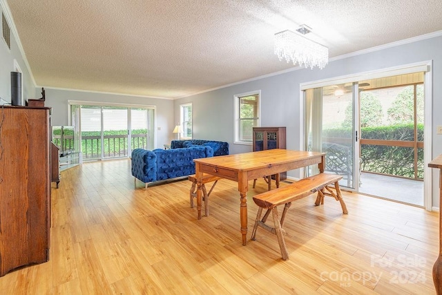 dining area with a textured ceiling, light hardwood / wood-style flooring, ornamental molding, and a notable chandelier