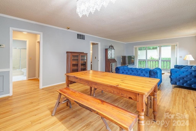 dining area featuring light hardwood / wood-style floors, ornamental molding, a textured ceiling, and a chandelier