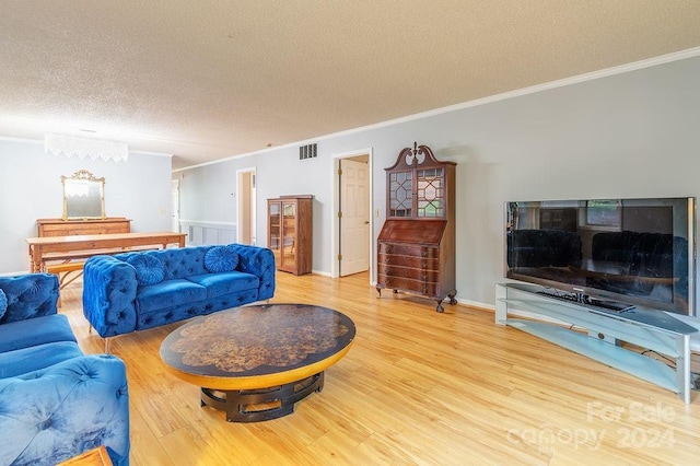 living room featuring hardwood / wood-style flooring, ornamental molding, and a textured ceiling