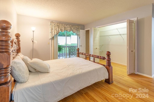 bedroom with access to outside, wood-type flooring, and a textured ceiling