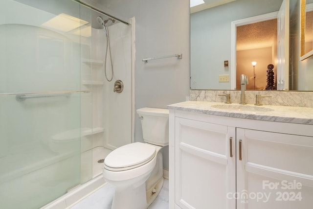 bathroom with a shower with door, vanity, and toilet