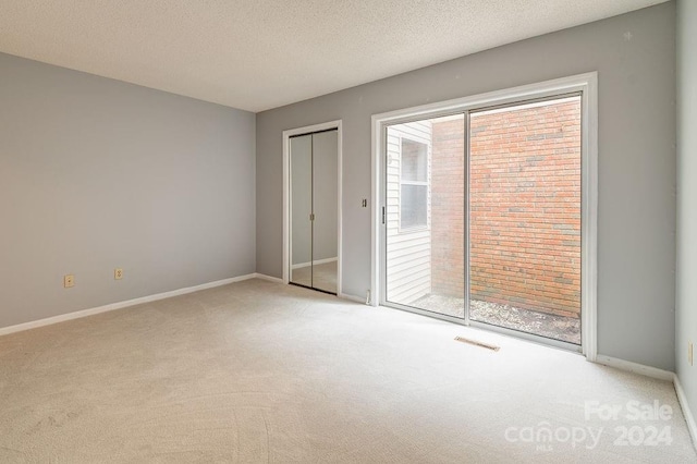 unfurnished bedroom with light colored carpet and a textured ceiling