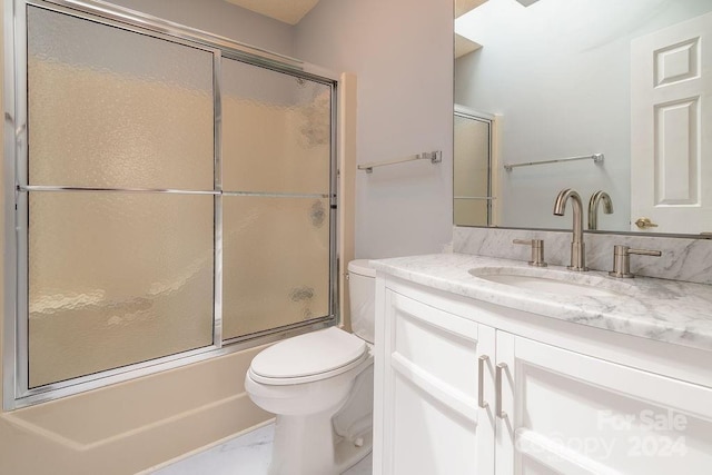 full bathroom featuring combined bath / shower with glass door, vanity, and toilet