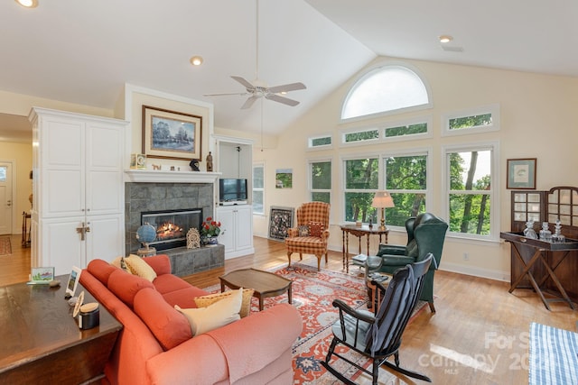 living room with a tile fireplace, ceiling fan, high vaulted ceiling, and light wood-type flooring