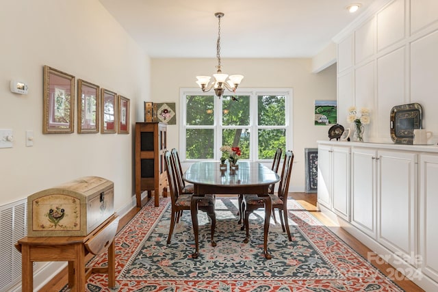 dining room with light hardwood / wood-style floors and an inviting chandelier