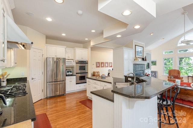 kitchen with white cabinetry, sink, light hardwood / wood-style floors, a kitchen bar, and appliances with stainless steel finishes