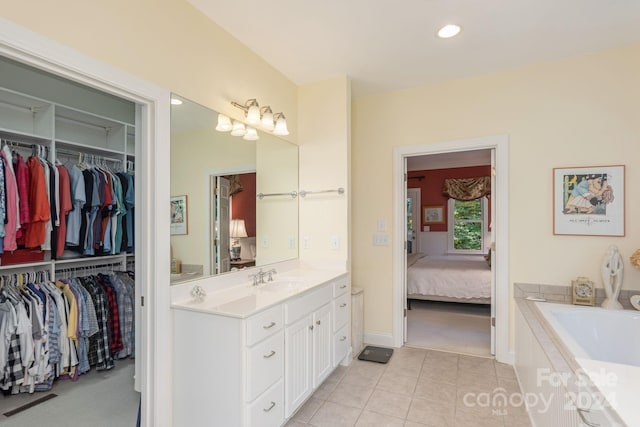 bathroom with tile patterned floors, tiled bath, and vanity