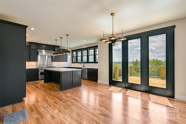 kitchen featuring appliances with stainless steel finishes, a center island, light hardwood / wood-style floors, sink, and hanging light fixtures