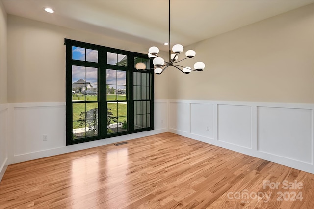 unfurnished dining area featuring an inviting chandelier and light hardwood / wood-style floors