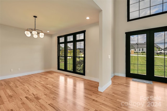 foyer with french doors, an inviting chandelier, and light hardwood / wood-style flooring